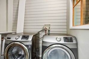 Two front-loading washing machines with a 10-year warranty, connected to a power outlet on a white wall.