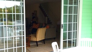 A room with a sliding glass door leading to a balcony, a staircase, and a dining area with a table and chairs.