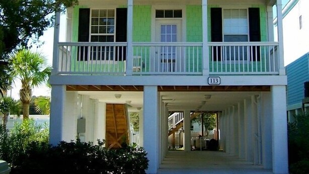 A two-story house with a green roof, white trim, and a balcony on the upper floor.