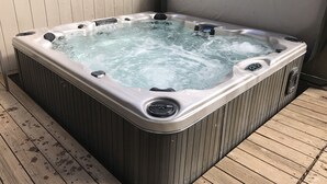 Un jacuzzi con panel de control, rodeado de cubierta de madera.