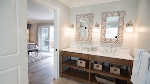 A bathroom with a double vanity, two large mirrors with decorative frames, and a wooden vanity with storage drawers.