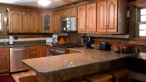 A kitchen with wooden cabinets, a stainless steel microwave, a stove, and a dishwasher. - Beautiful secluded Log Home - Nestled in the country! (Wright City)