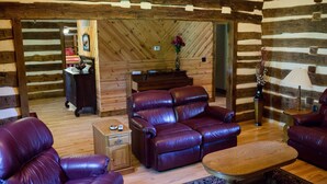 A log cabin interior with leather sofas, a wooden coffee table, and a fireplace. - Beautiful secluded Log Home - Nestled in the country! (Wright City)