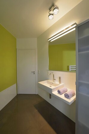 Ein modernes Badezimmer mit einem weißen Waschbecken, zwei Spiegeln und einer Tür.