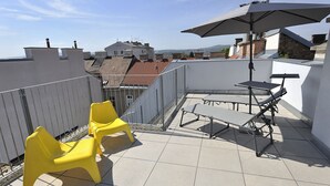 A rooftop terrace with yellow chairs, a table, and an umbrella. - Modern, Architect-Designed Penthouse Loft With 2 Outdoor Roof Terraces (Vienna)