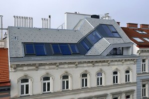 Ein Gebäude mit einem geneigten Dach, mehreren Oberlichtern und einer klassischen Fassade mit Rundbogenfenstern.