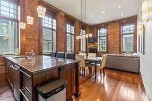 A modern kitchen with a central island, dining area, and a built-in fireplace.