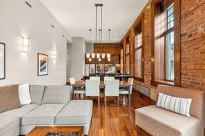 A modern living room with a gray sofa, a coffee table, and a dining area with a wooden table and chairs.