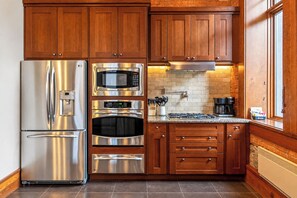 A modern kitchen with stainless steel appliances, wooden cabinets, and a brick backsplash.