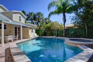 Un patio trasero con piscina, muebles de jardín y una zona de estar cubierta.