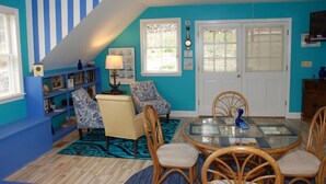 A dining area with a glass-top table, wooden chairs, and a blue patterned rug.