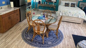 A compact, well-organized room with a kitchen, dining area, and a bed.