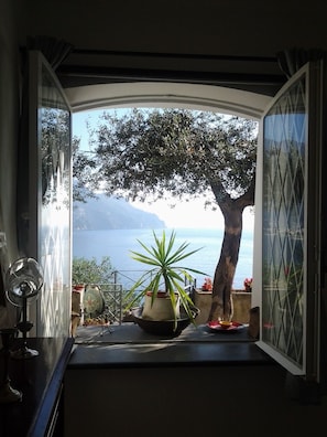 Enjoy a serene view of the water from this room's large window, overlooking a tree-lined balcony.