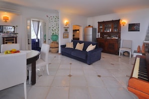 Relax in this spacious living room with a piano, dining table, and kitchen area.