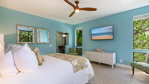 A bedroom with a bed, a ceiling fan, a dresser, a chair, and a TV. - Hula On In to Beach House Chic Style, Click the Video tour below! (Wailea)