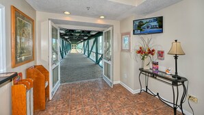 A hallway with a view of a bridge, framed artwork, a television, and a table with a lamp and flowers.