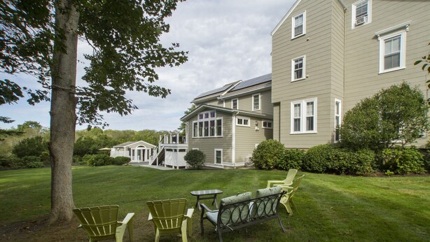 A residential property with a well-maintained lawn, outdoor seating area with chairs and a table, and a large house with multiple windows and a covered porch. - Desireable Coggeshall Ave - 2-Bdrm Units - 3rd  Floor, sleeps 4 (Newport)