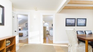 A room with a dining table, chairs, a wooden shelf, and a rug. - Desireable Coggeshall Ave - 2-Bdrm Units - 3rd  Floor, sleeps 4 (Newport)