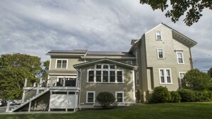 A two-story house with a front porch, a small front yard, and a staircase leading to the upper level. - Desireable Coggeshall Ave - 2-Bdrm Units - 3rd  Floor, sleeps 4 (Newport)