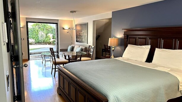 Quarto com uma cama grande, área de refeições e vista para o exterior.