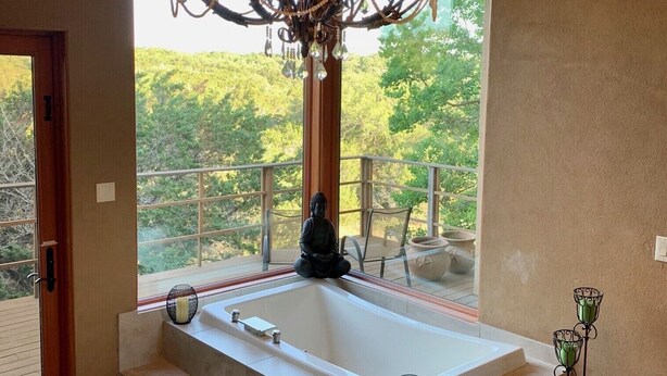Un baño moderno con una bañera independiente, una araña y una estatua de Buda.