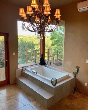 A modern bathroom with a freestanding bathtub, a chandelier, and a Buddha statue. - Scenic Hill Country Views in New Braunfels (New Braunfels)