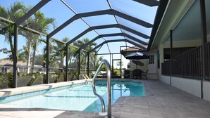 Una piscina interior con techo de cristal, rodeada de palmeras y un patio.