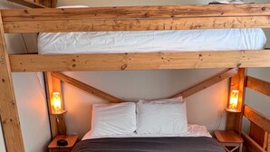 A bunk bed with two levels, each with a wooden frame and white bedding. There are two bedside tables with lamps on either side of the bed. - Private Hot Tub. Ski In & 15 Minute Walk to the Elk Chair (Fernie)