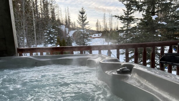 A hot tub with a wooden deck and a view of a snowy forest. - Private Hot Tub. Ski In & 15 Minute Walk to the Elk Chair (Fernie)