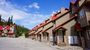 A row of multi-story buildings with red roofs, stone pillars, and a clear sky. - Private Hot Tub. Ski In & 15 Minute Walk to the Elk Chair (Fernie)
