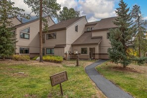 A multi-story residential building with a landscaped front yard, a driveway, and a mailbox.