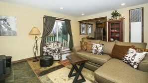 A living room with a sofa, armchair, and ottoman, a lamp, and a painting on the wall. - Gorgeous Lakeside hideout with views of the lake and mountains (Big Bear Lake)