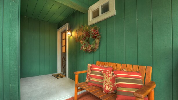 A wooden bench with striped cushions and a decorative wreath on a green wall. - Gorgeous Lakeside hideout with views of the lake and mountains (Big Bear Lake)