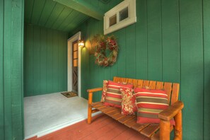 Un banc en bois avec des coussins à rayures et une guirlande décorative sur un mur vert.