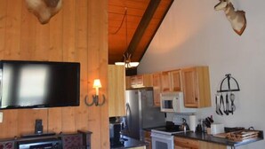 Une cuisine dotée de meubles en bois, d’un four à micro-ondes, d’un réfrigérateur et d’un téléviseur à écran plat fixé au mur.