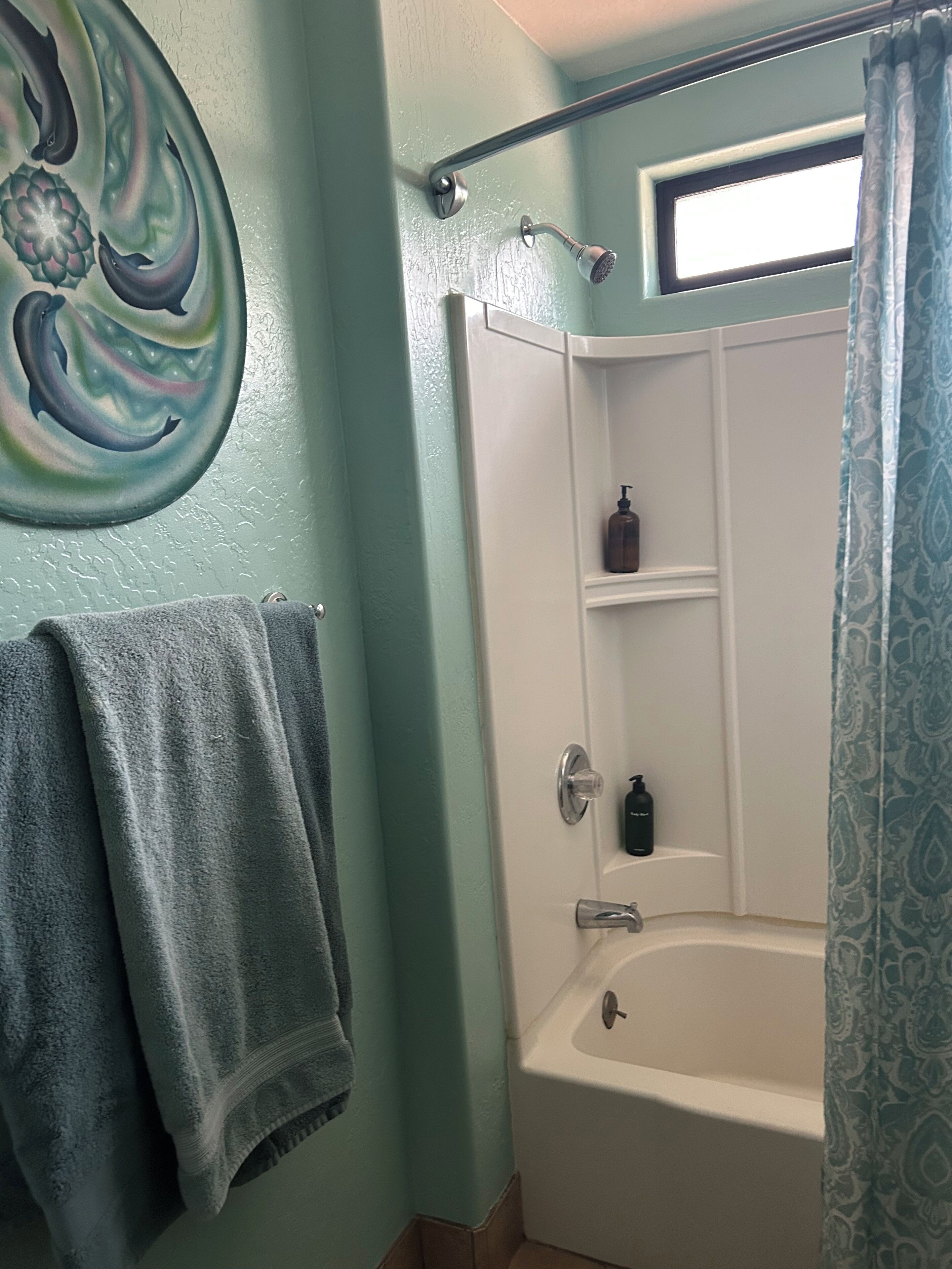 A bathroom with a bathtub, a shower, and a towel rack.