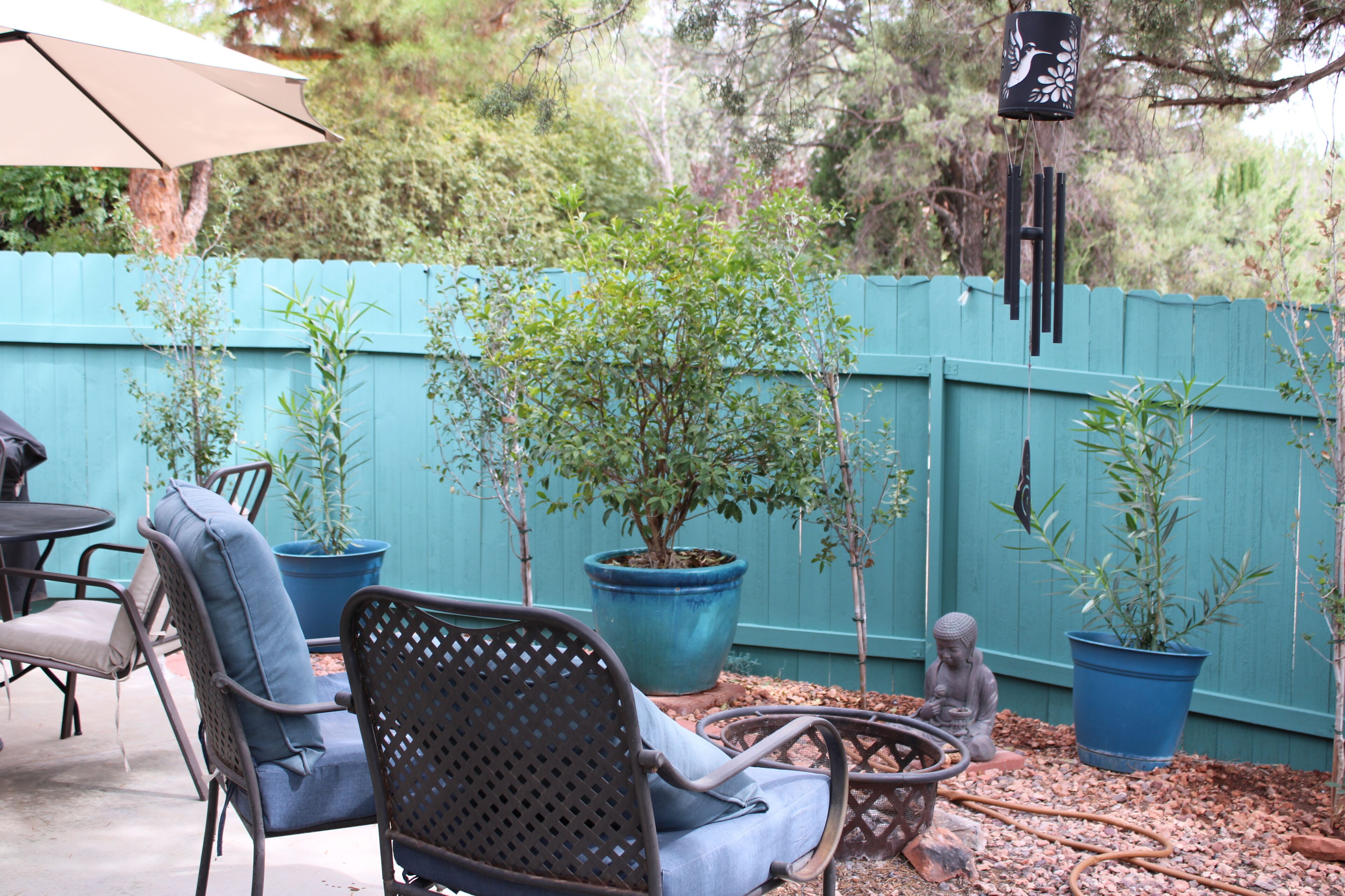 A patio area with outdoor furniture, a blue fence, and potted plants.