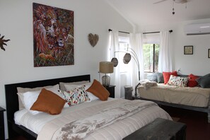 A bedroom with a large bed, a smaller bed, a painting of lions, and a window with curtains. - Red Rock Retreat: Hot tub, walk to creek for swimming,. (Sedona)