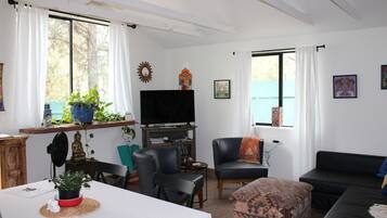 Una sala de estar con televisor, asientos y objetos decorativos.