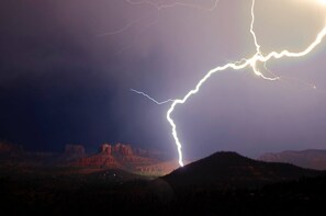 Un éclair illuminant un paysage montagneux la nuit.