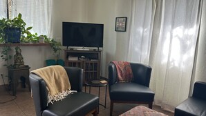 Un salon équipé d’un téléviseur à écran plat, de deux fauteuils en cuir, d’une petite table et d’une bibliothèque.