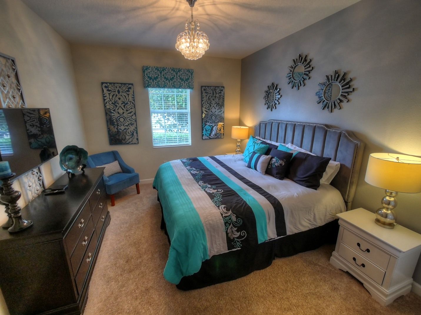 A bedroom with a bed, dresser, nightstand, and decorative wall art.