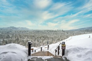 A snow-covered staircase leading to a viewpoint with a sign indicating video monitoring.