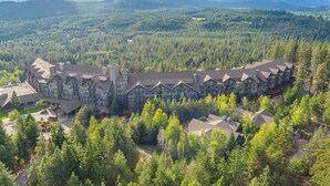 A large lodge with multiple buildings, surrounded by dense forest and mountains in the background. - 4070 Wilderness Retreat with Modern Amenities! (Cle Elum)