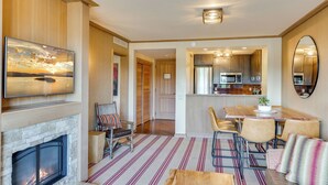 A modern living room with a fireplace, a dining area with a table and chairs, and a kitchen in the background. - 4070 Wilderness Retreat with Modern Amenities! (Cle Elum)
