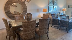 A dining area with a round mirror, wicker chairs, and a chandelier.