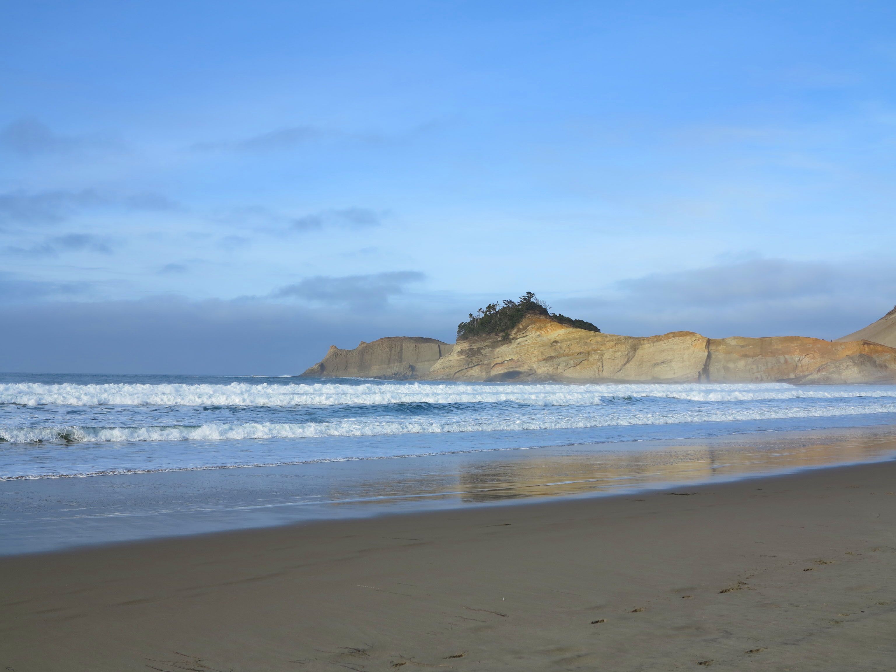 A beach with a rocky outcrop and waves.