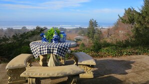 A stone table with a checkered tablecloth and blue vases, overlooking a coastal landscape. - Gorgeous Ocean View! Private. Cozy Comfort. (Neskowin)