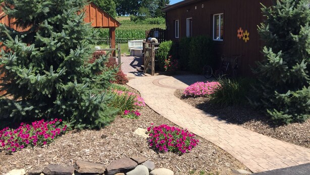 A garden with a wooden building, a paved walkway, and a wooden fence.
