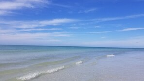 Een strand met heldere lucht en rustig water.